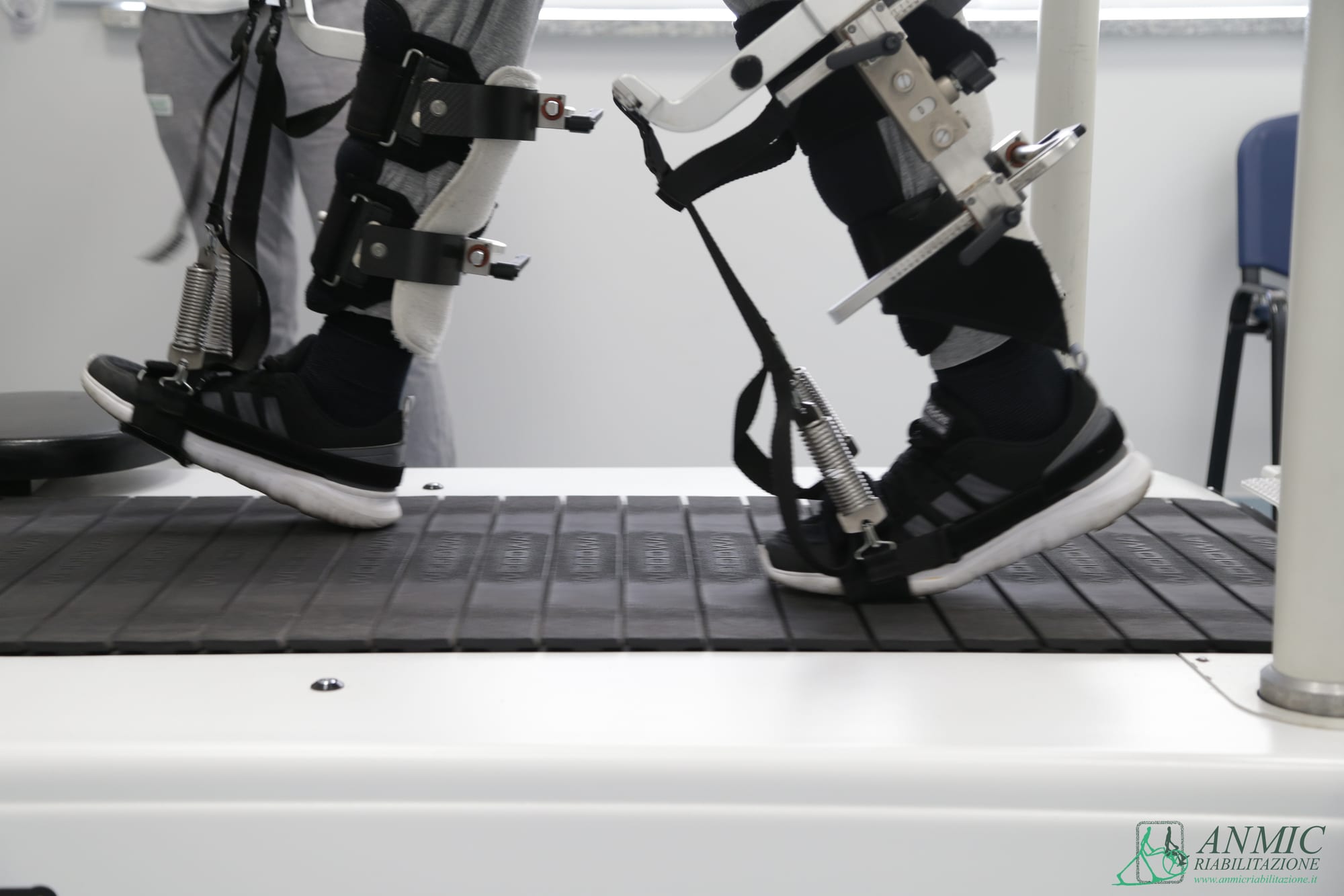 Dettaglio di tutori robotizzati (esoscheletro) alle gambe di un paziente su tapis roulant