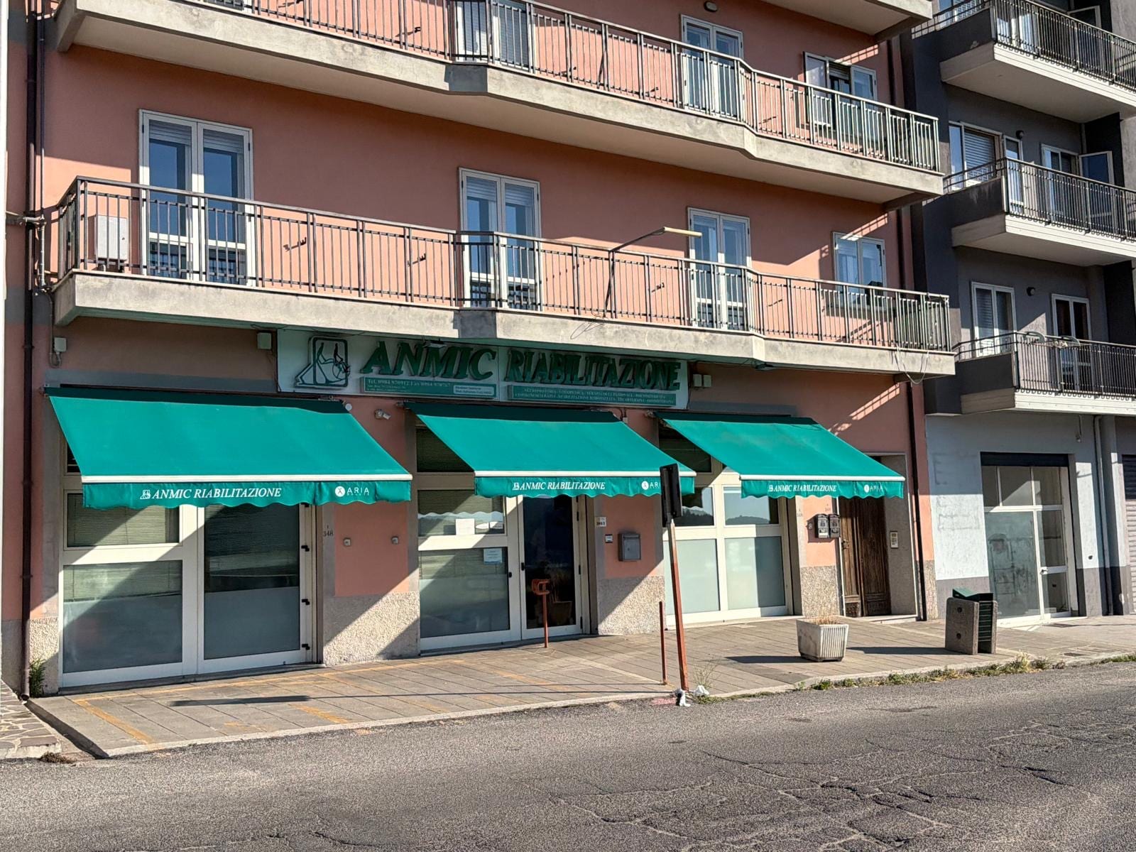 Ingresso della sede di San Giovanni in Fiore: vetrine con tende verdi e insegna ANMIC Riabilitazione